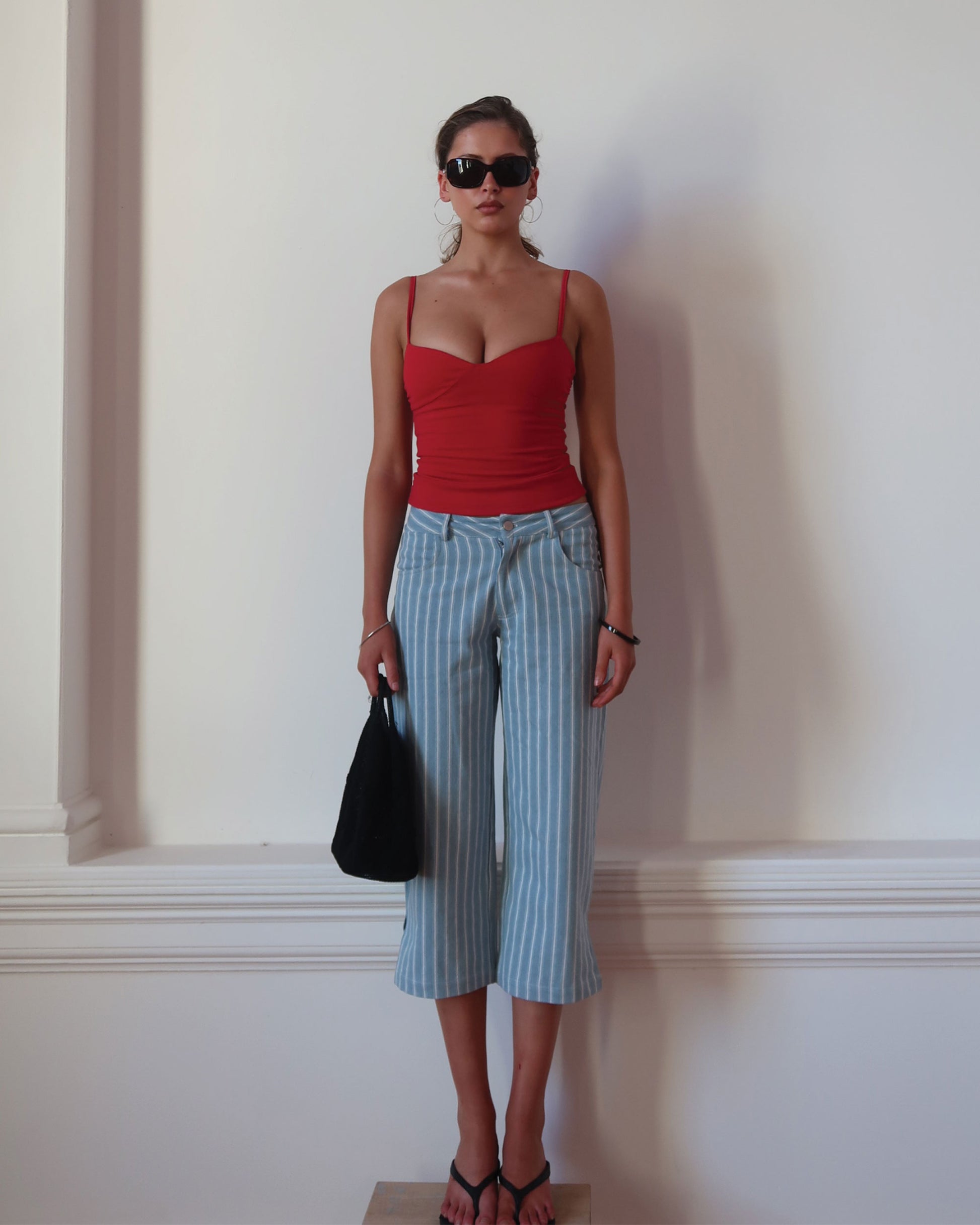 Women's singlet top in deep red colour featuring figure-hugging fit, contoured waist, and bust gathering.